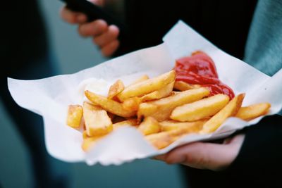 Cropped image of hand holding french fries with ketchup