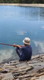 Rear view of man sitting by lake