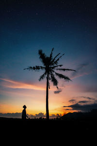 Silhouette man standing by tree against sky during sunset