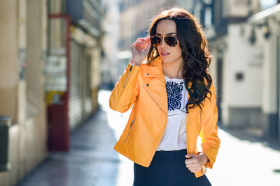Young woman in sunglasses standing on footpath