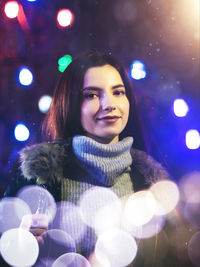 Portrait of smiling woman in illuminated nightclub