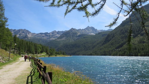 Rear view of person on lake by mountains against sky