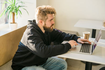 Side view of man using laptop at home