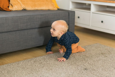 Side view of boy sitting on sofa at home