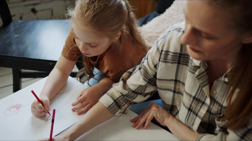 High angle view of mother and daughter drawing at home