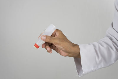 Midsection of man holding bottle against white background