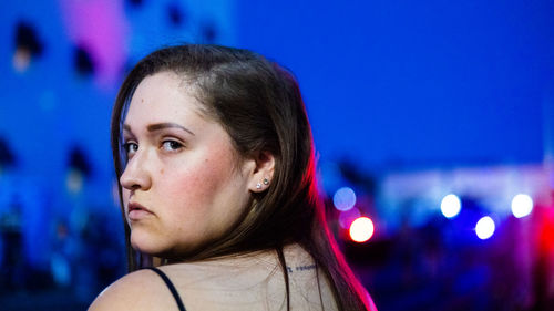 Woman looking over her shoulder alone at night in the city 