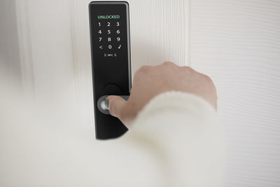 Woman unlocking smart door of house with fingerprint