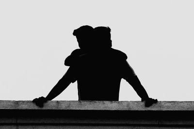 Rear view of silhouette man sitting against clear sky