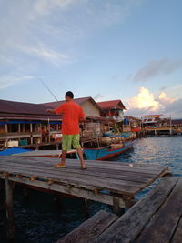 Rear view of man on pier against sky