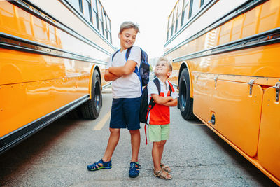 Full length of boys standing by bus