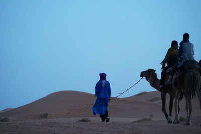 Rear view of man riding horse in desert