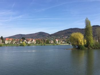 Scenic view of river by buildings against sky