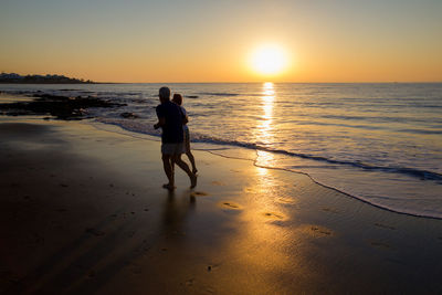 People running on beach at sunset