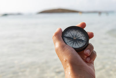 Close-up of hand holding ring over sea