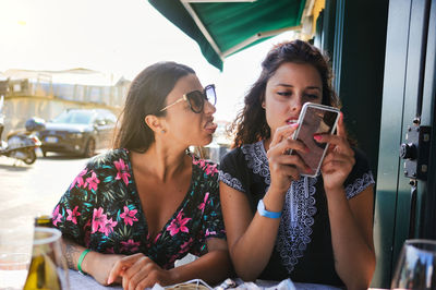 Young woman using mobile phone while sitting at restaurant