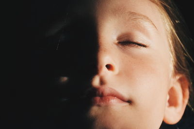 Sunlight falling on girl with eyes closed in darkroom