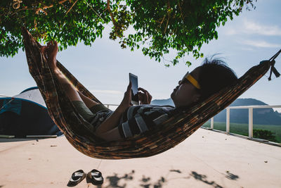 Woman using mobile phone while relaxing in hammock