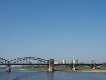 Bridge over river against clear blue sky