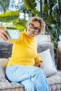 Portrait of young woman sitting on bed at home