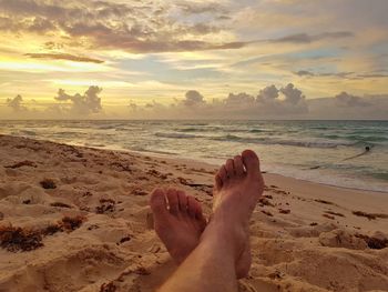 Low section of woman sitting on sand at beach