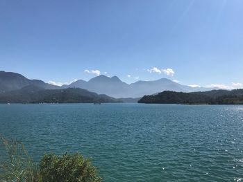 Scenic view of lake and mountains against clear blue sky