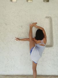 Full length of young woman lying on wall