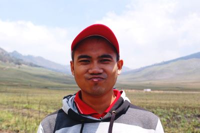 Portrait of smiling man standing on field against sky