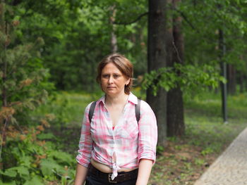 A woman walks in the summer in the park in sunny weather, she walks along a forest path. 