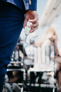 Midsection of woman holding champagne flute while standing outdoors