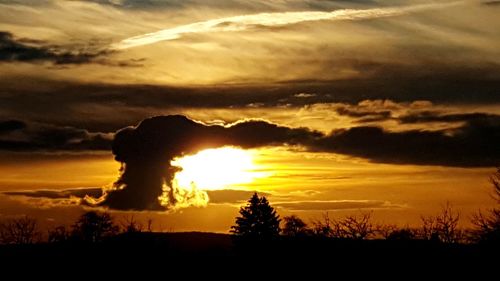 Silhouette landscape against dramatic sky during sunset