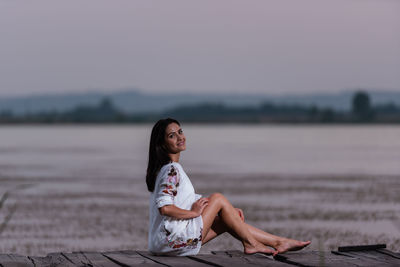 Side view of woman sitting on land