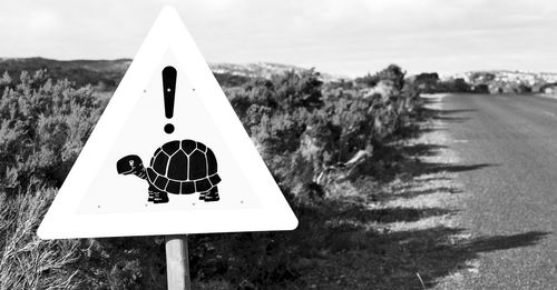 Close-up of sign on road against sky