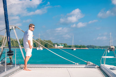 Man standing in boat on sea against sky