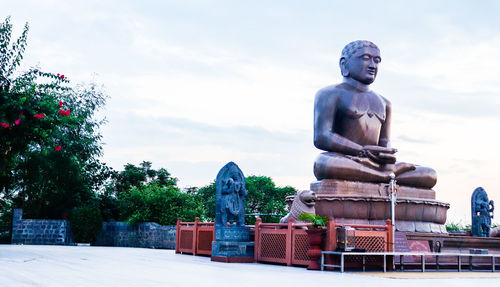 Statue against trees and plants against sky