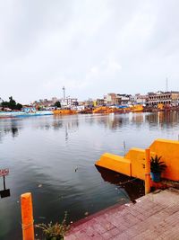 Boats in river by buildings in city against sky