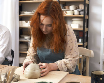 Beautiful young red head woman potter crafts dishes, tableware, utensils. pottery workshop class.