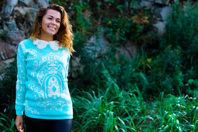 Young woman standing against rock formation in forest