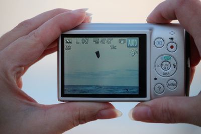 Cropped hand photographing sea with digital camera