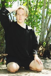 Young man sitting on tree