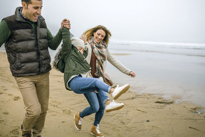 Happy parents lifting up daughter on the beach in winter