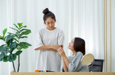 Side view of smiling young woman sitting on table