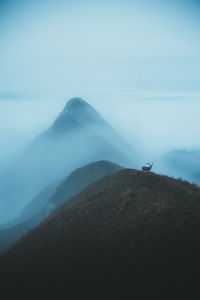 Scenic view of mountains against sky in foggy weather