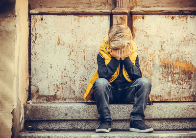 Upset boy crying while sitting alone on staircase.