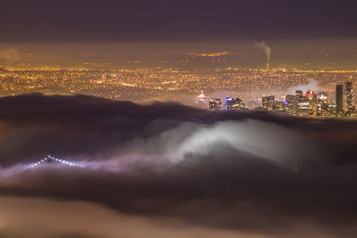 Aerial view of illuminated residential district and clouds at night