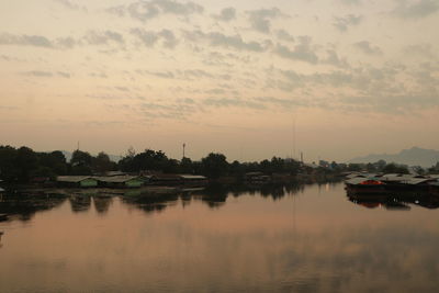 Boats moored in lake against sky during sunset