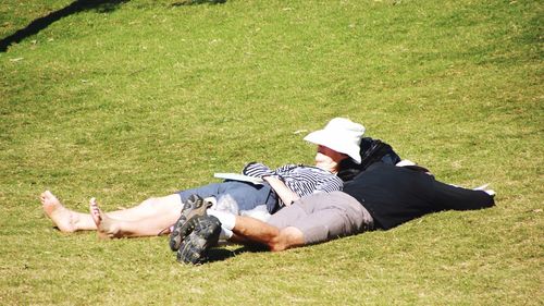 Side view of young man lying on grassy field