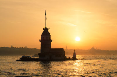 Maiden tower amidst sea against sky during sunset