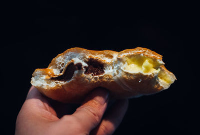 Cropped hand of person holding food against black background