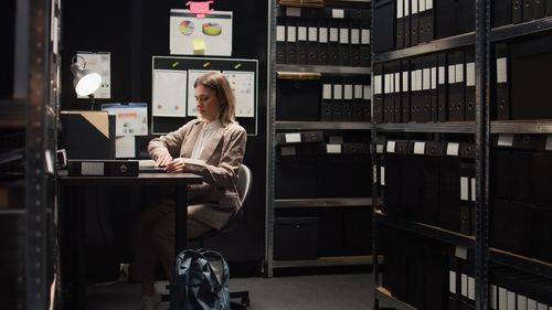 Side view of woman using mobile phone in library